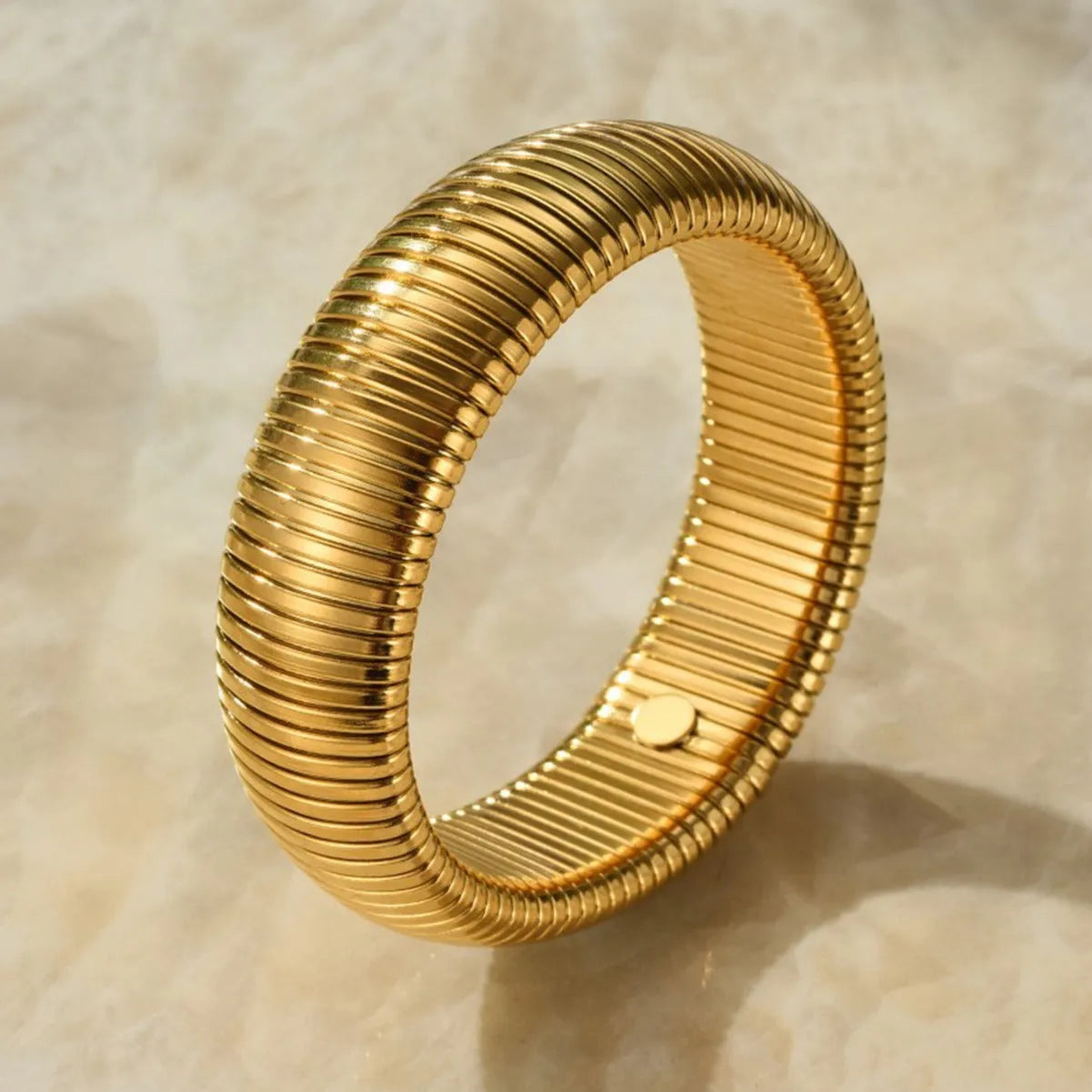 Women's titanium steel elastic bracelet with a vertical stripe pattern in gold, shown on a wrist.