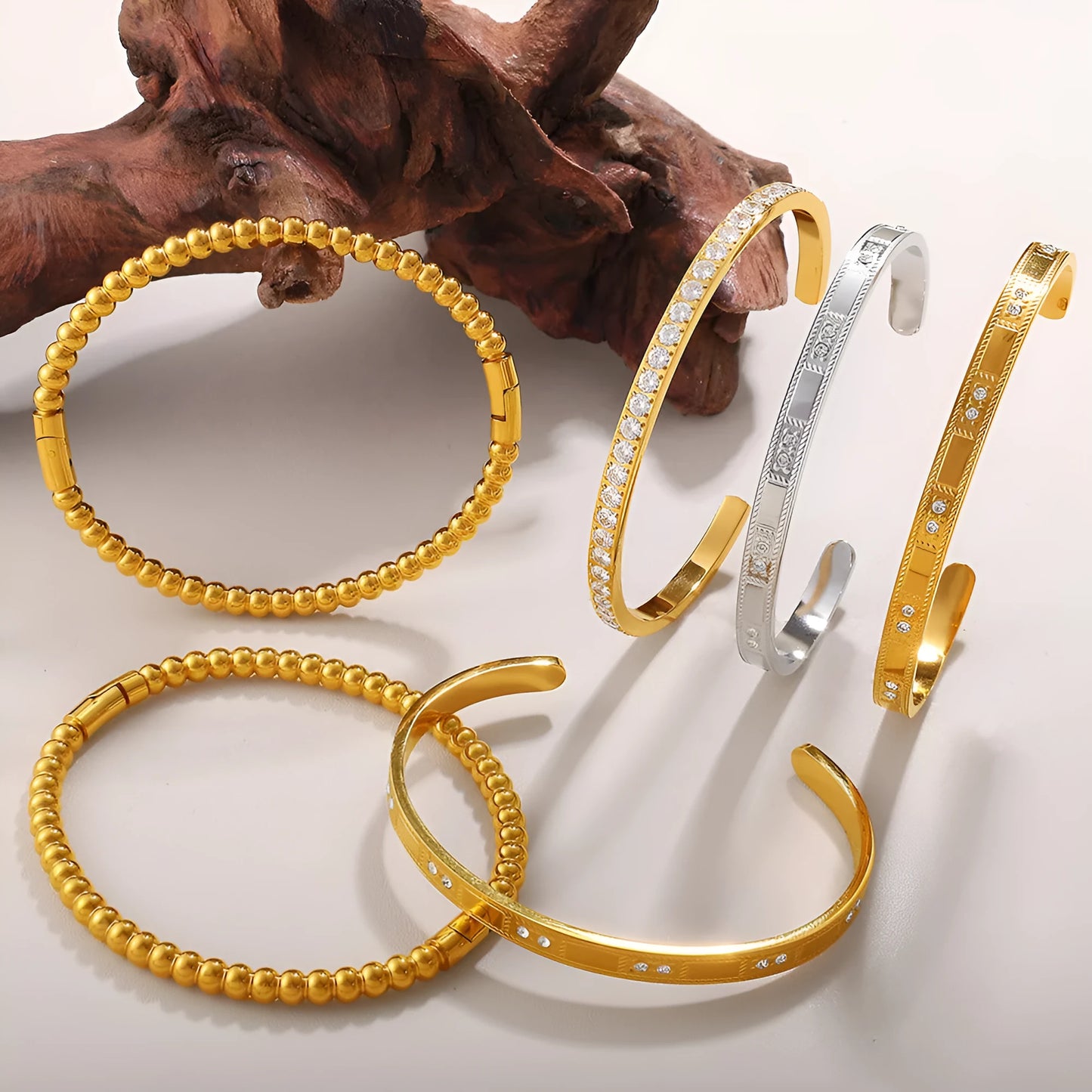 Stainless steel open-end bracelet with a buckle clasp in a gold electroplated finish featuring circle design elements.