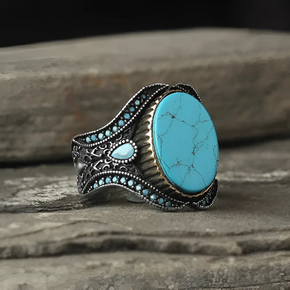 Men's round antique silver alloy ring with a turquoise centre stone on a finger.