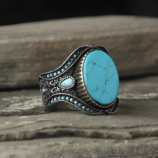 Men's round antique silver alloy ring with a turquoise centre stone on a finger.