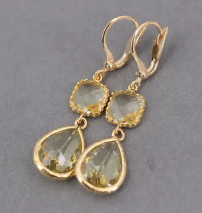 Gold geometric drop earrings with long crystal fringe and water droplet design.
