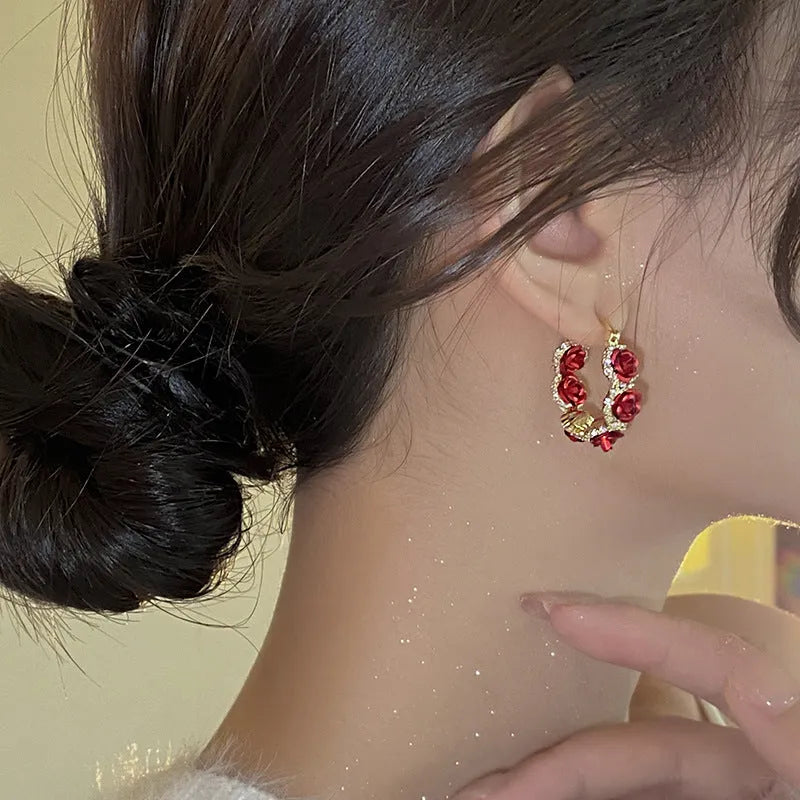 Red alloy rose flower earrings with ear clip fastening shown as complete pair