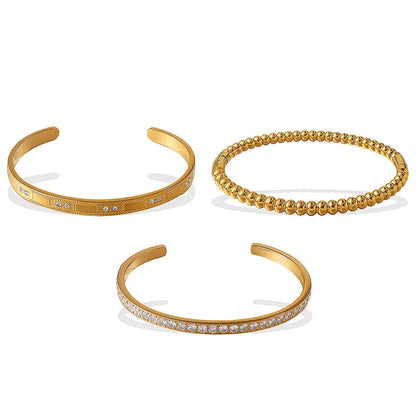Stainless steel open-end bracelet with a buckle clasp in a gold electroplated finish featuring circle design elements.