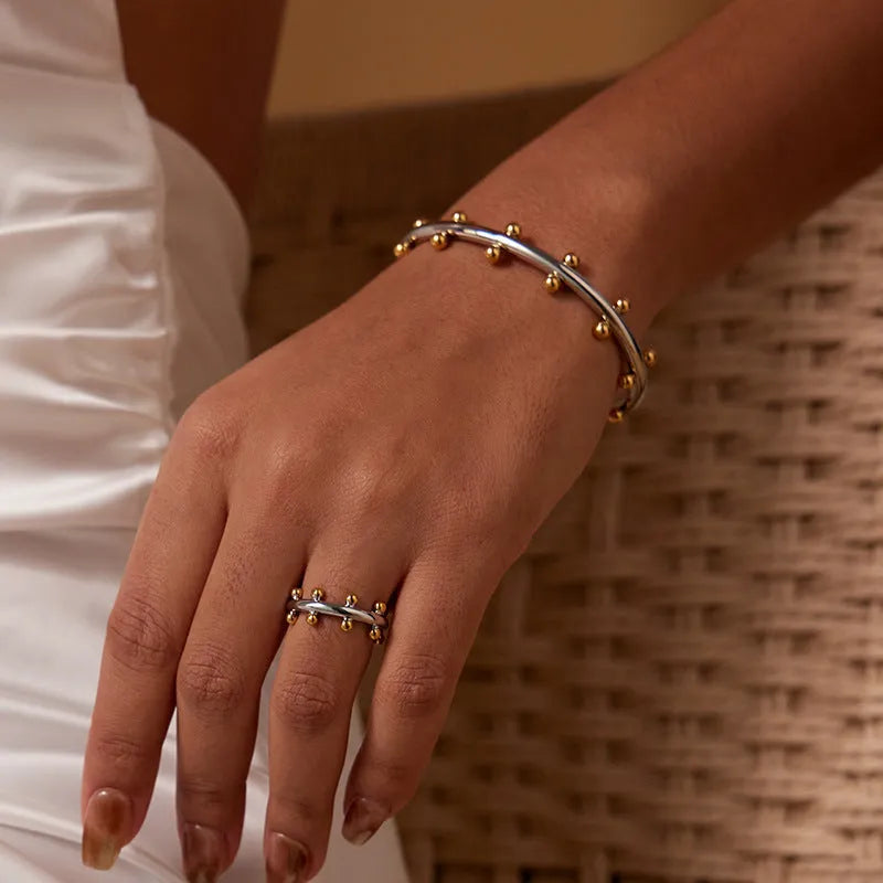 C-shaped stainless steel bracelet with textured rivets and bean beads in gold finish
