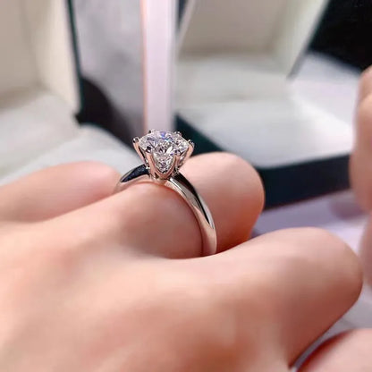 White gold plated geometric ring with a six-claw set zircon stone on a model's finger.