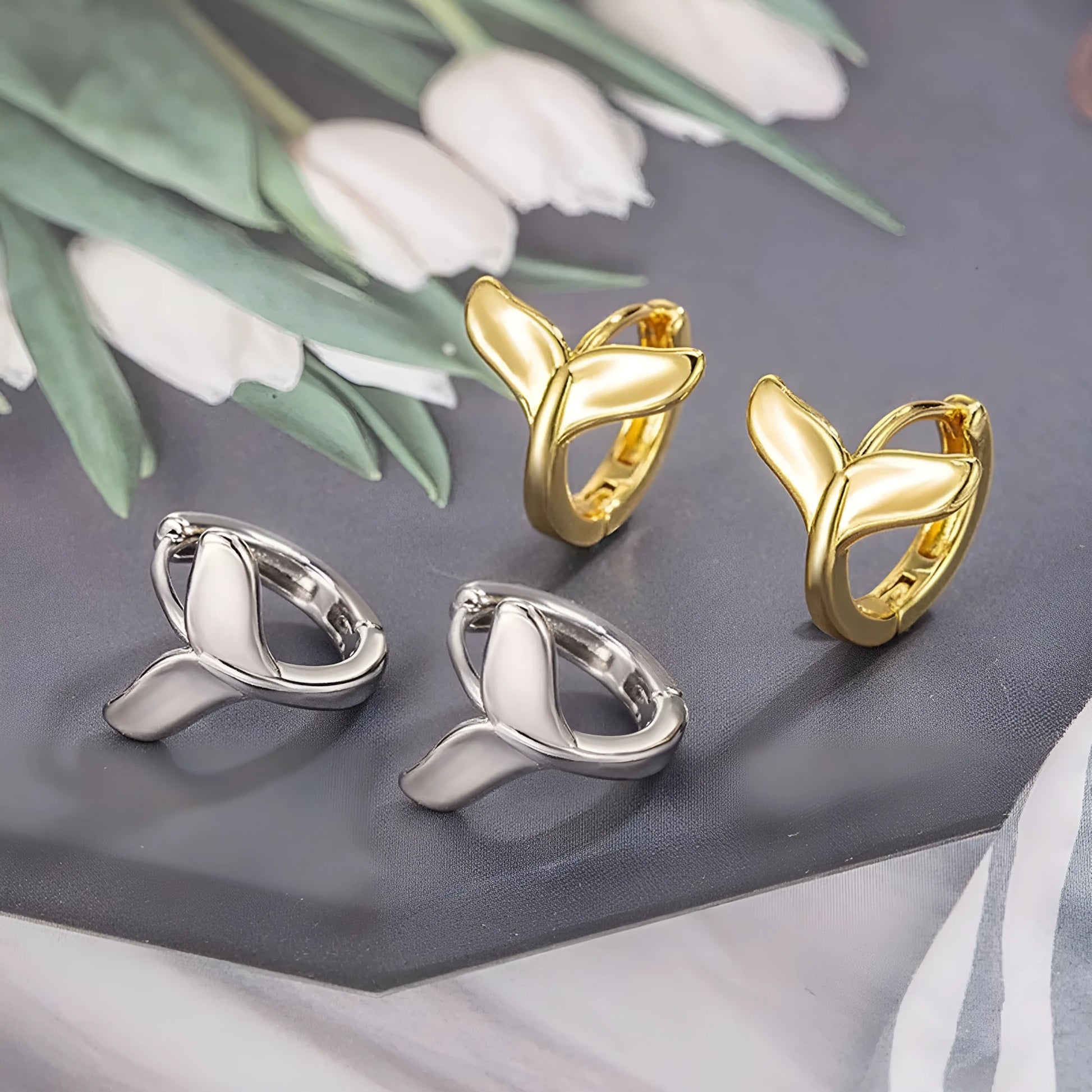 A pair of women's simple fishtail drop earrings with a gold electroplated finish on a copper base.