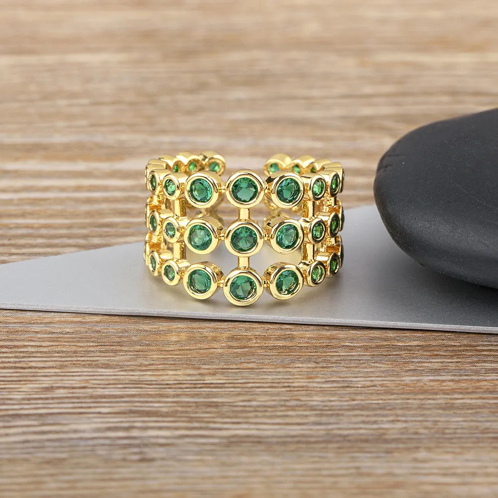 Wide gold plated copper ring with a full band of sparkling green cubic zirconia stones on a hand.