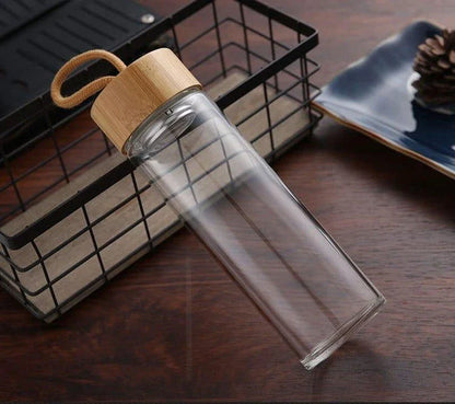 Elegant glass water bottle with bamboo lid and string, a sustainable and fashionable hydration solution