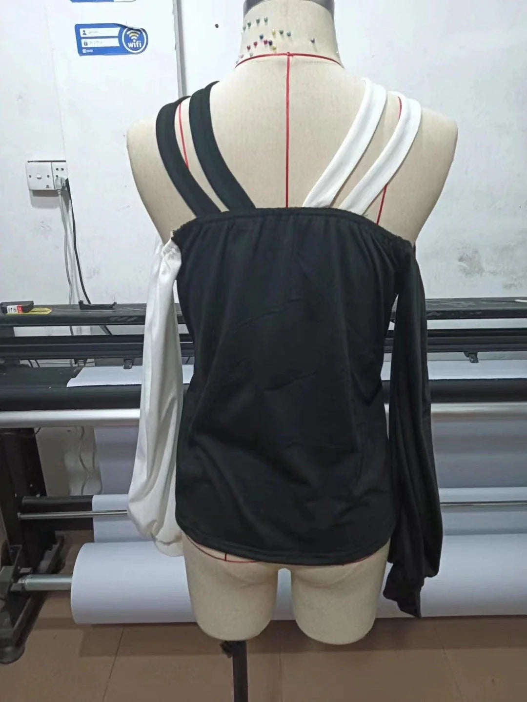 A stylish women's top with a black and white patchwork design, featuring a cross-belt accent for a fashionable casual look.