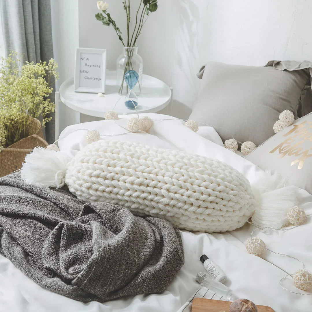 Soft and fluffy white chunky knit pillow in the shape of a candy with a kawaii tassel design, perfect for adding a playful touch to your home decor.