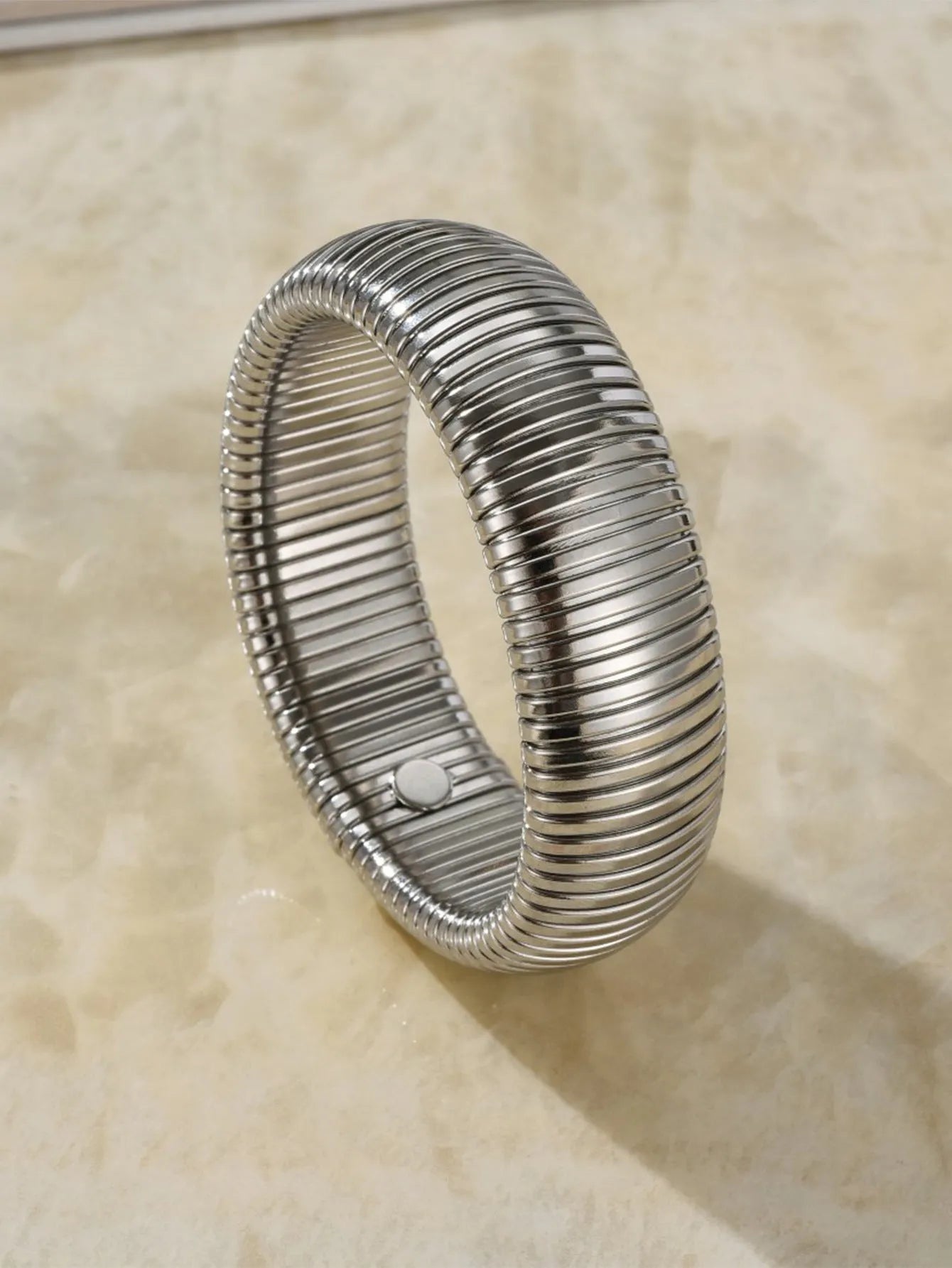 Women's titanium steel elastic bracelet with a vertical stripe pattern in gold, shown on a wrist.