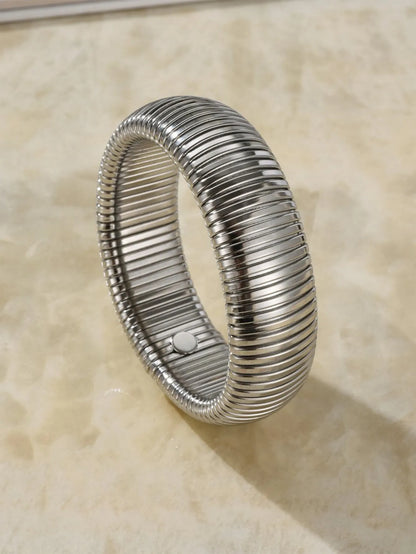 Women's titanium steel elastic bracelet with a vertical stripe pattern in gold, shown on a wrist.