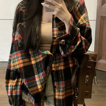 A woman modelling a loose-fit black, green, and purple plaid shirt with long sleeves.