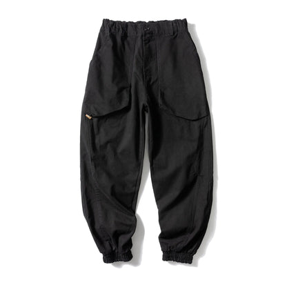 Black cotton casual pants with large pockets, tapered legs, and ankle ties on a hanger.