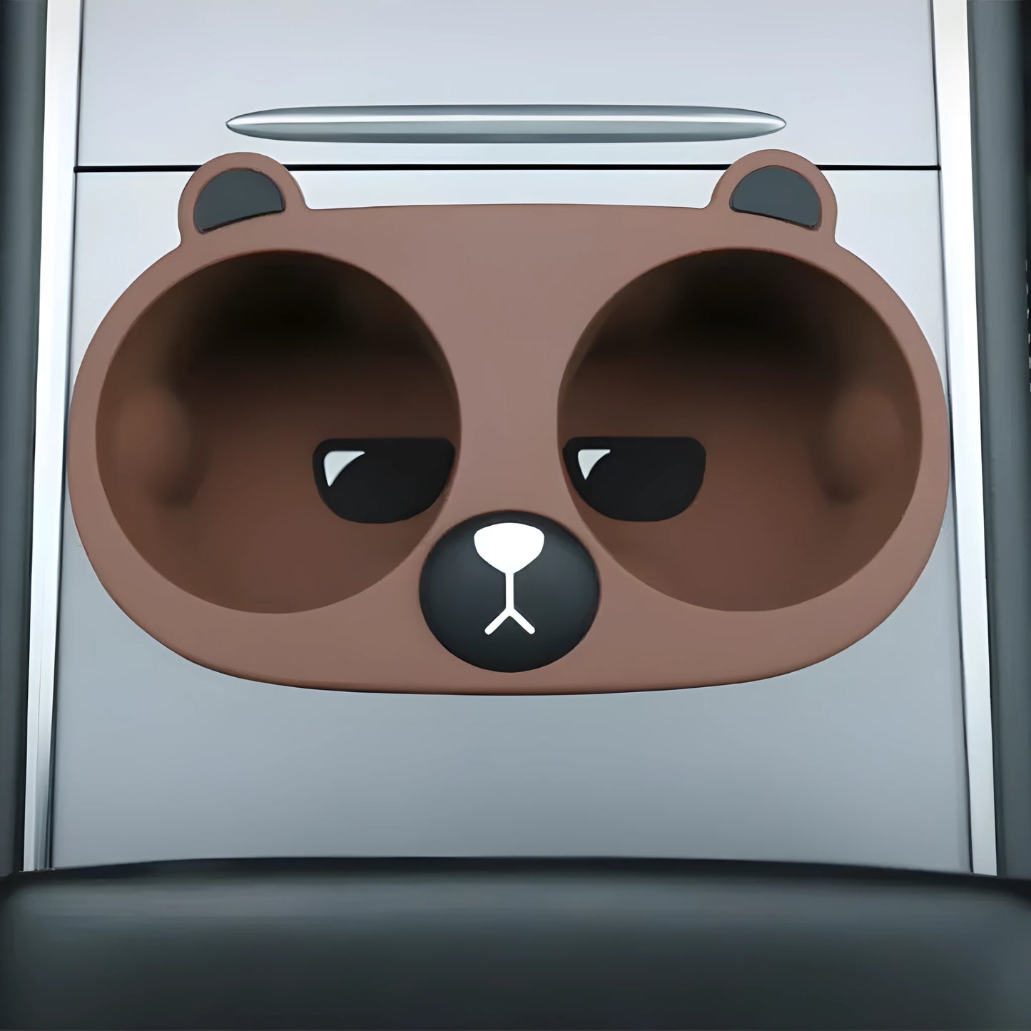 Flexible grey silicone car cup holder insert with a raised cartoon animal design for the centre console.