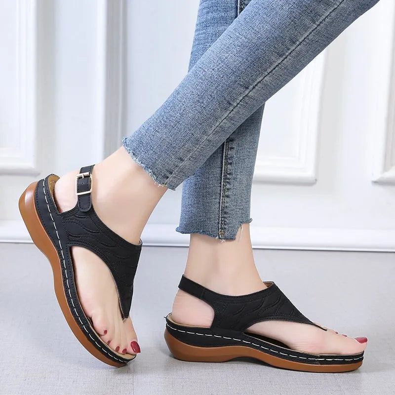 Women's wedge heel flip flop sandals in black with adjustable back strap on a light background