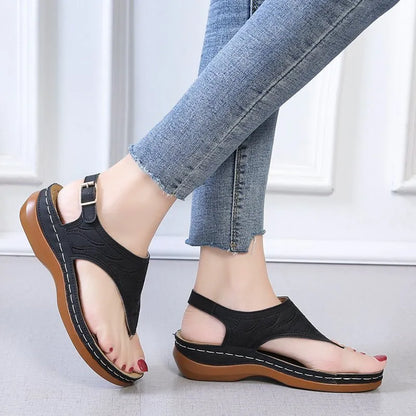 Women's wedge heel flip flop sandals in black with adjustable back strap on a light background