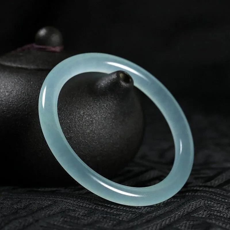 Jade bracelet with floating flower patterns and auspicious cloud motifs in green stone with polished finish