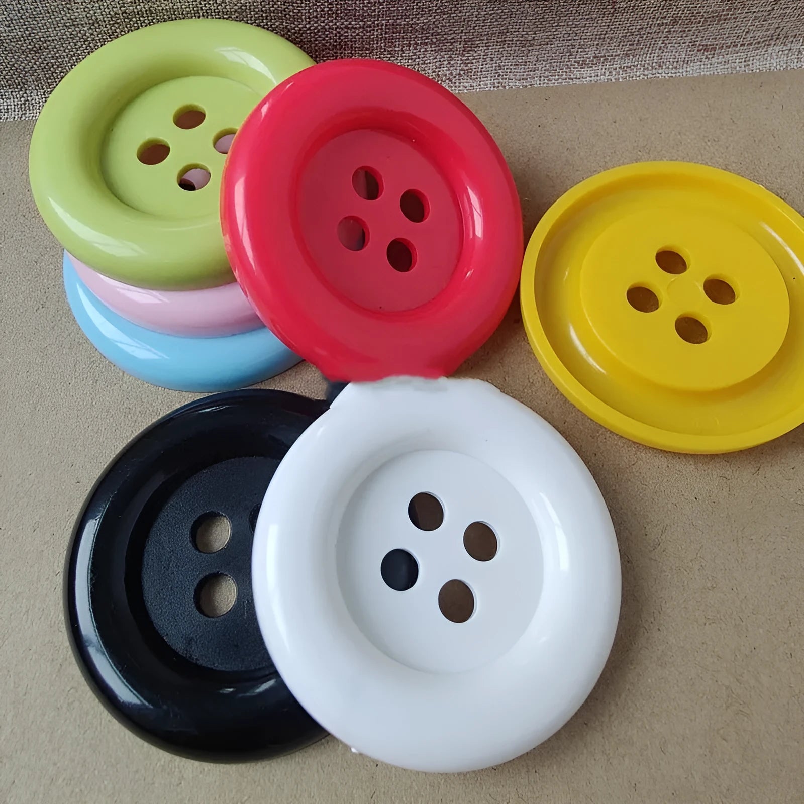 Assorted oversized round plastic buttons in various colours showing four-hole sew-through design.