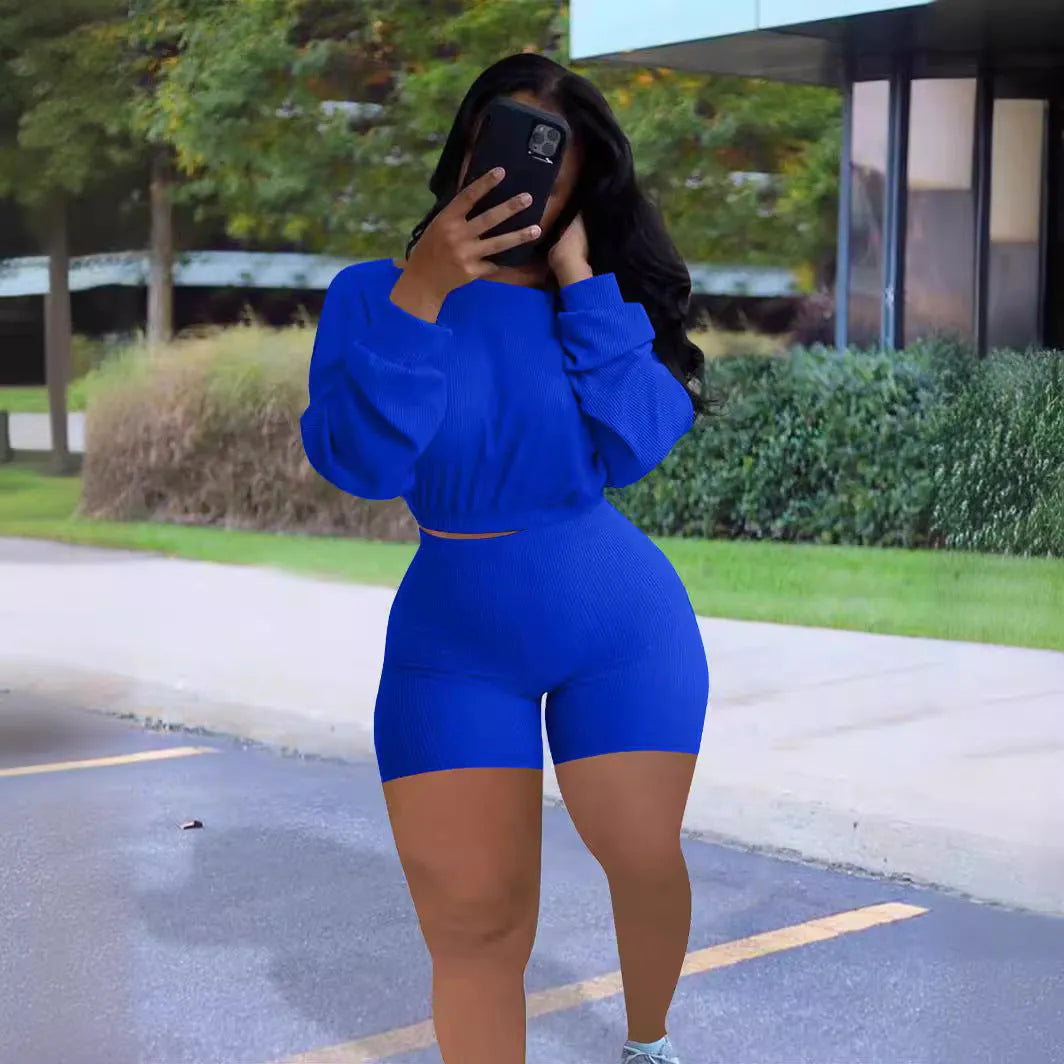 Women's long sleeve off-the-shoulder top and shorts two-piece set in a solid colour.
