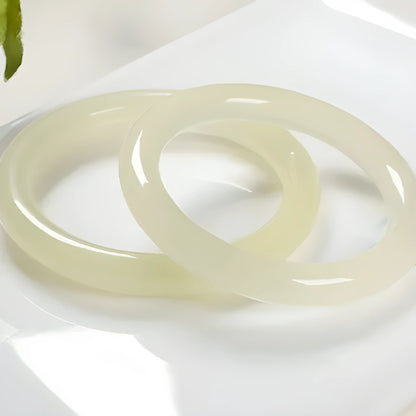 Ice-like silk jade bracelet with winding silk design and round bar beads on a wrist.