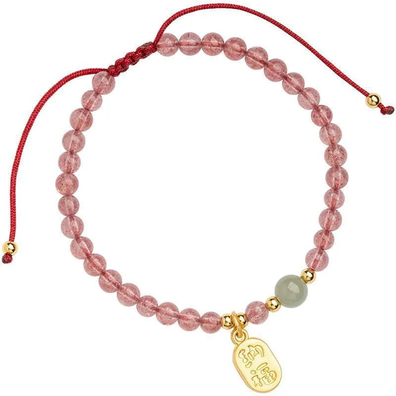 A hand-woven red rope bracelet with a strawberry quartz or garnet crystal, shown in simple styling.
