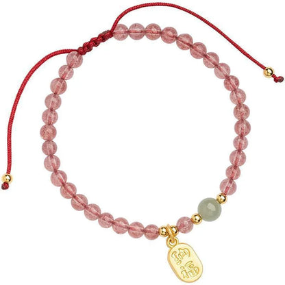 A hand-woven red rope bracelet with a strawberry quartz or garnet crystal, shown in simple styling.
