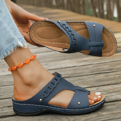 Blue roman style slippers with a slope heel and fish mouth toe holder on a wooden floor.