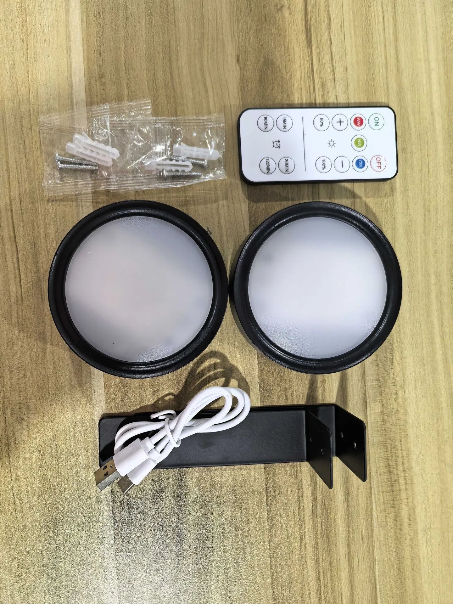 Black magnetic LED painting lamp with remote control on a white wall.