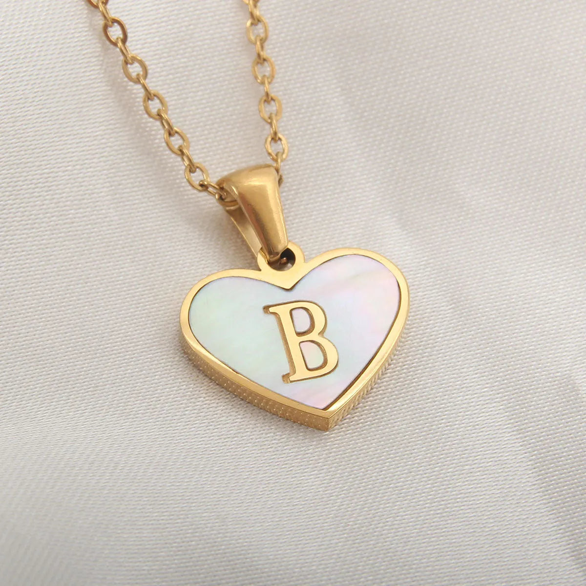 Gold-plated clavicle necklace with a white shell heart pendant, personalised with a letter from A to Z.