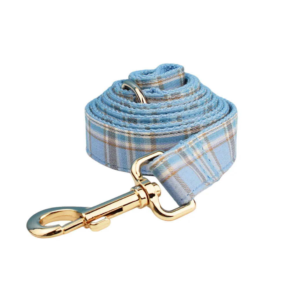 Sky blue grid pattern fabric dog collar, leash, vest, and bow set on a white background.