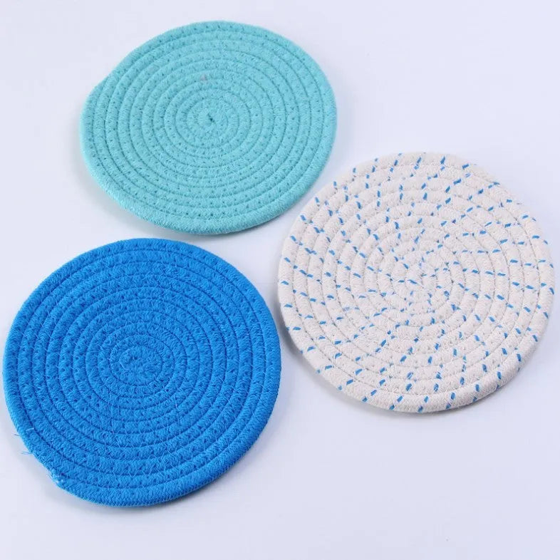 Set of three round grey cotton cord coasters, each 18cm in diameter, on a wooden table.