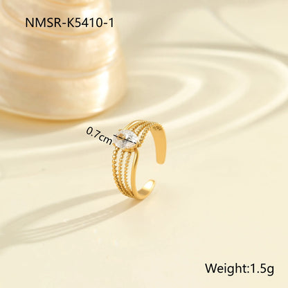 Gold electroplated stainless steel open mouth ring with geometric shapes and zircon inlay on a heart drop.