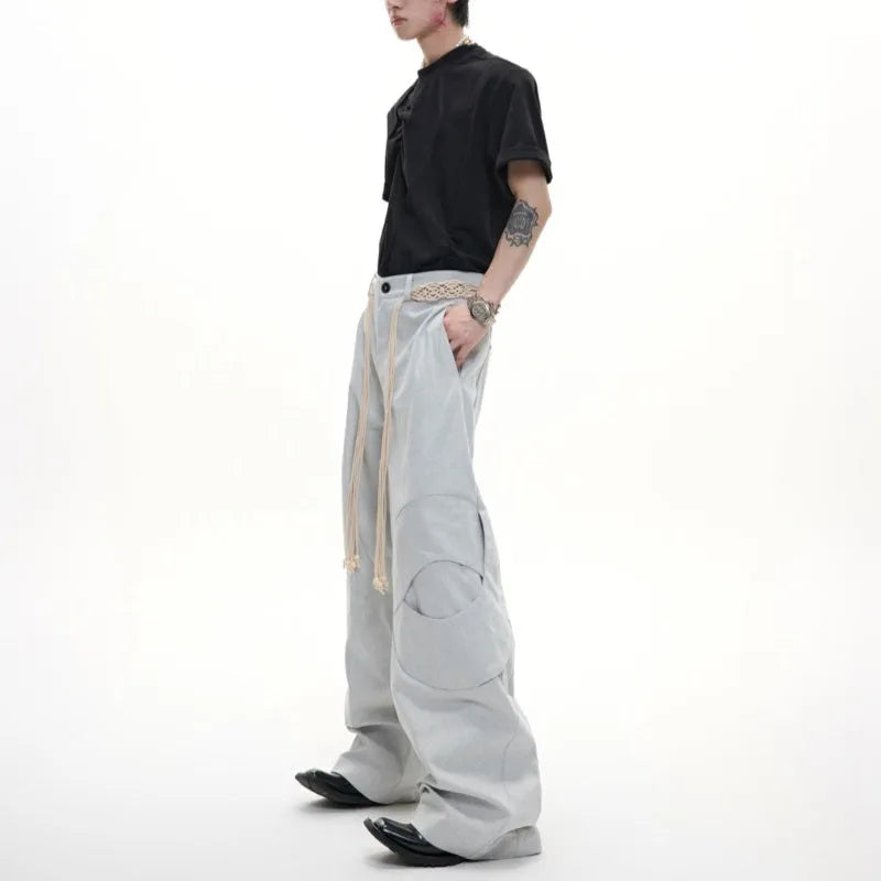 Men's dark blue straight-leg cotton jeans with 3D cutting, belt stitching, and decorative tassel on a hanger