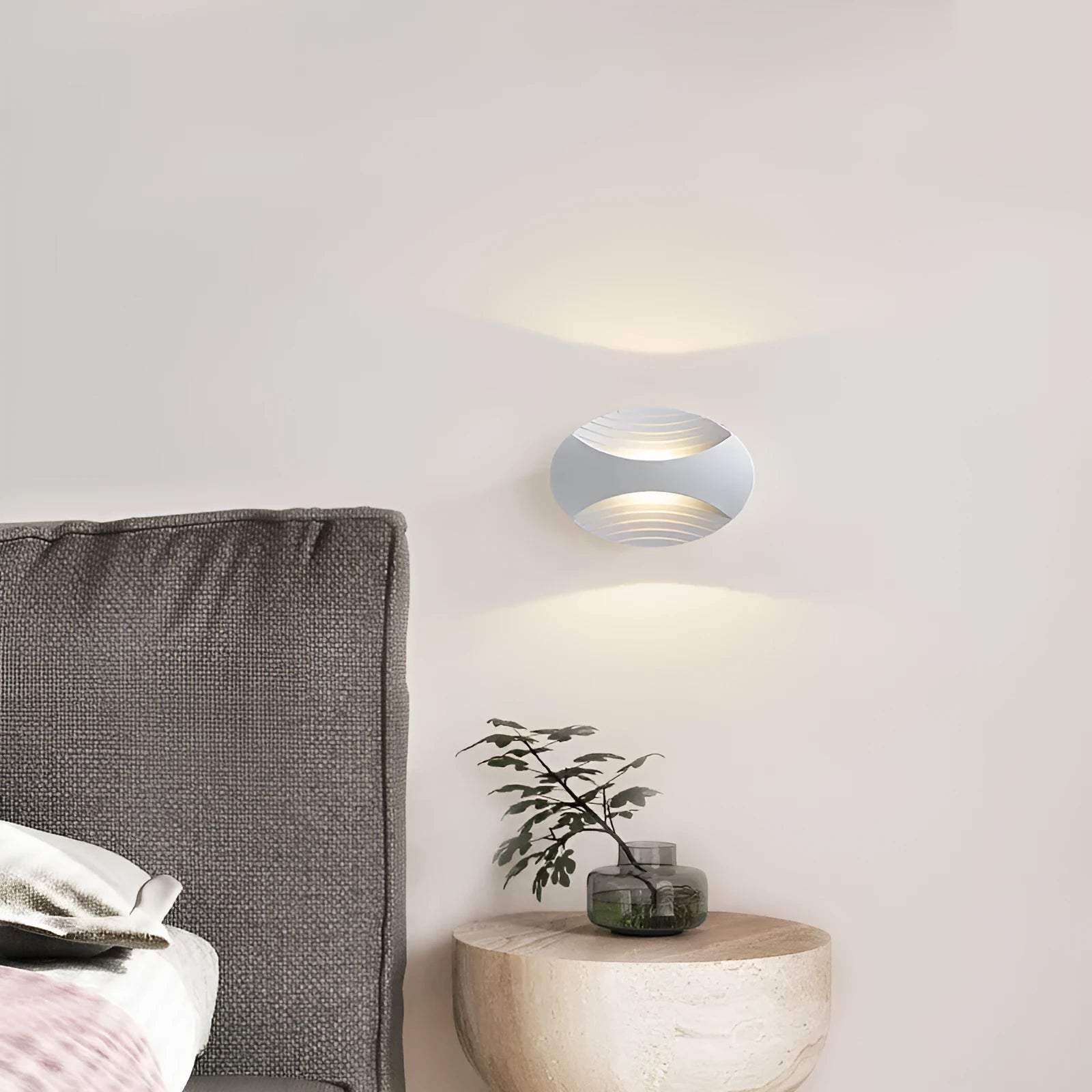 Modern aluminium wall lamp in black finish mounted beside a bed, emitting warm LED light.