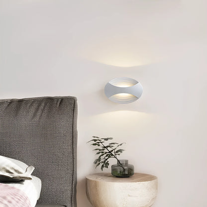 Modern aluminium wall lamp in black finish mounted beside a bed, emitting warm LED light.