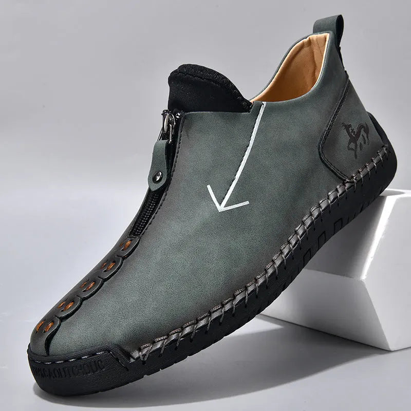 Men's black leather boots with front zipper, hand-stitched detailing, and rubber sole on a neutral background