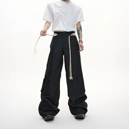 Men's dark blue straight-leg cotton jeans with 3D cutting, belt stitching, and decorative tassel on a hanger