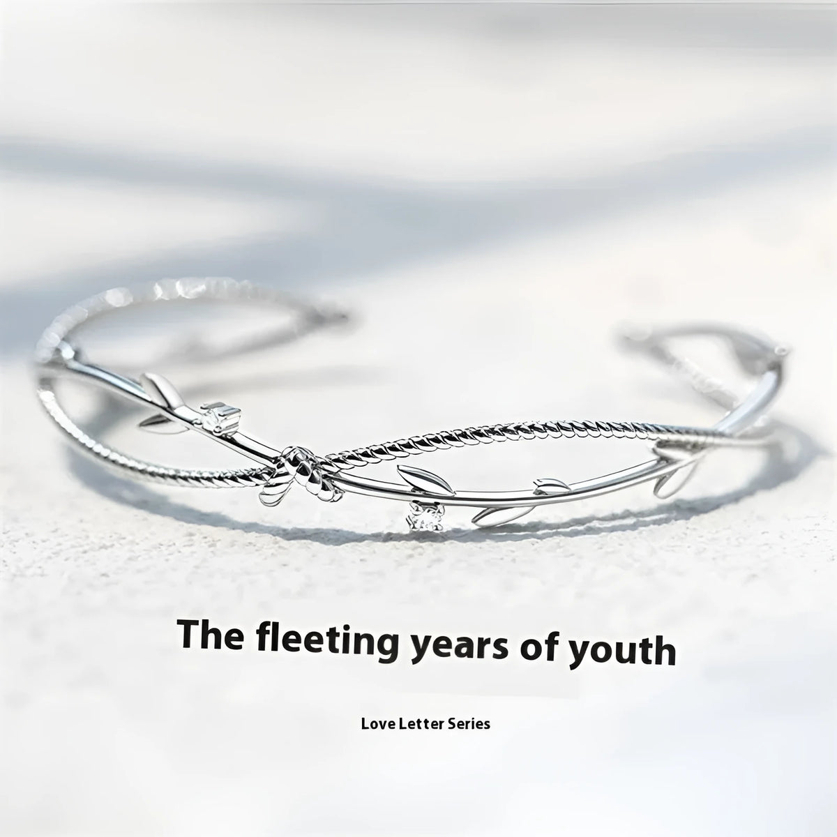 Close-up of a white gold coloured twisted copper bracelet with a branch and sprout design.
