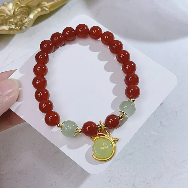 Close-up of a red agate bracelet featuring a detailed dragon design in a Chinese style.