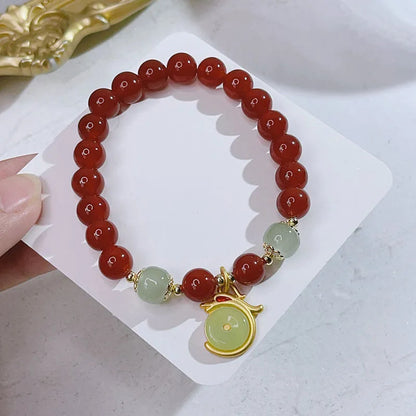 Close-up of a red agate bracelet featuring a detailed dragon design in a Chinese style.