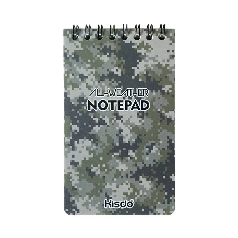 Spiral-bound waterproof notepad in camouflage colour, open on a desk with a pen, showing stone paper pages.