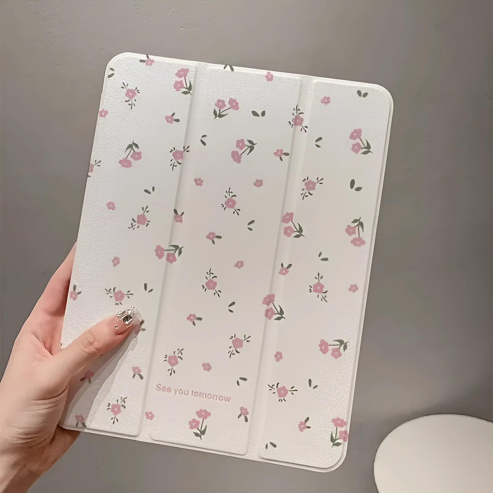 Transparent tri-fold iPad case with floral design, showing magnetic front cover and rear kickstand deployed.