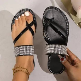 Women's flat beach sandals with a rhinestone-decorated toe strap in gold colour on a rubber sole.