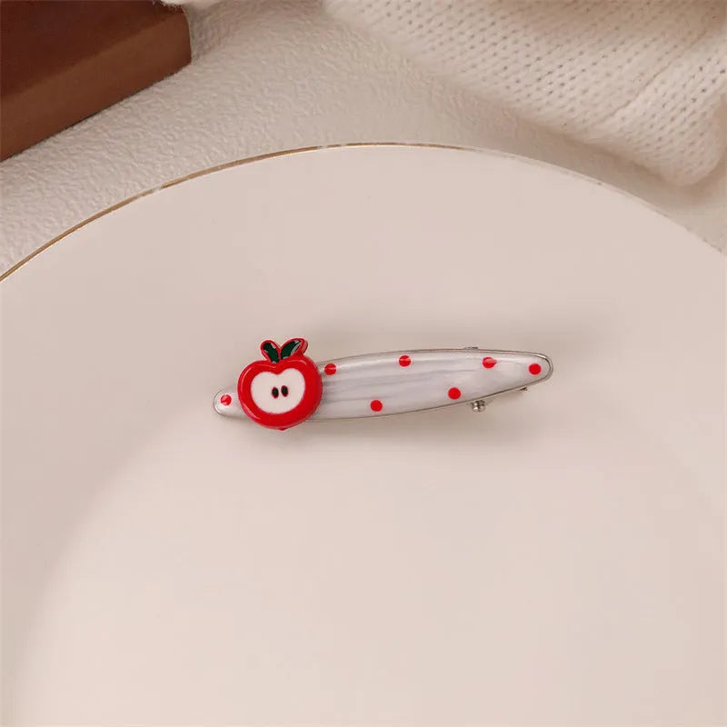 Red plastic hair clip with a 3D love heart and dots on a willow leaf-shaped base.