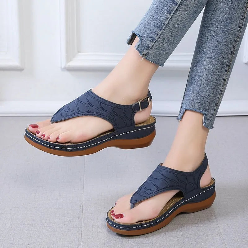 Women's wedge heel flip flop sandals in black with adjustable back strap on a light background