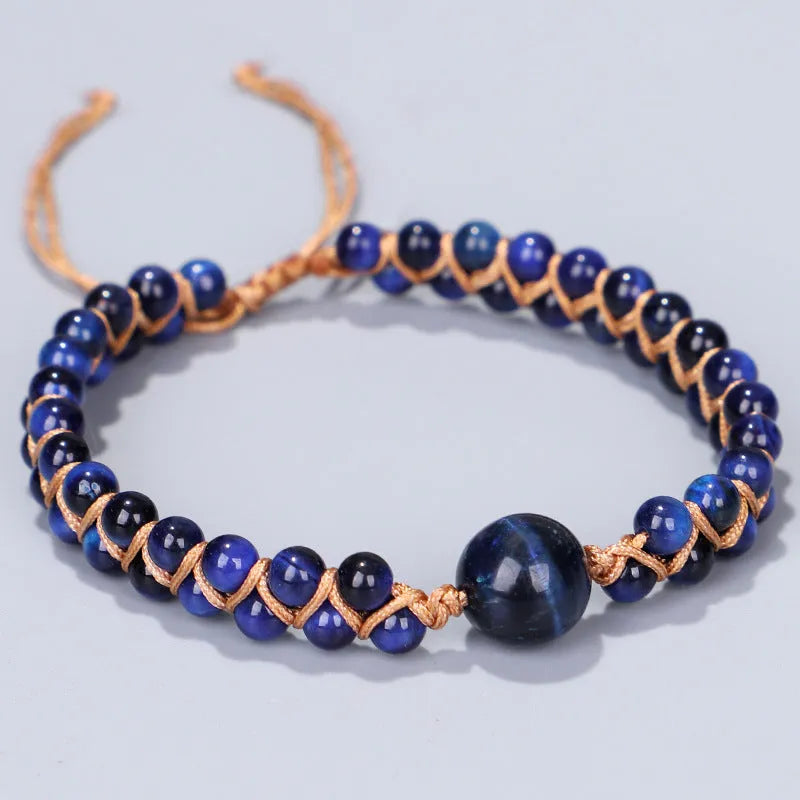 Handmade geometric pull bracelet woven from blue tigereye stone beads on a wrist.