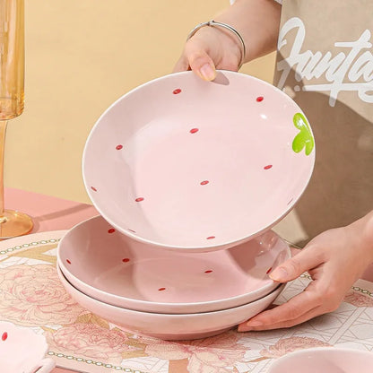 Porcelain dinnerware set with strawberry pattern, showing plates, bowls, and a twist spoon in various sizes