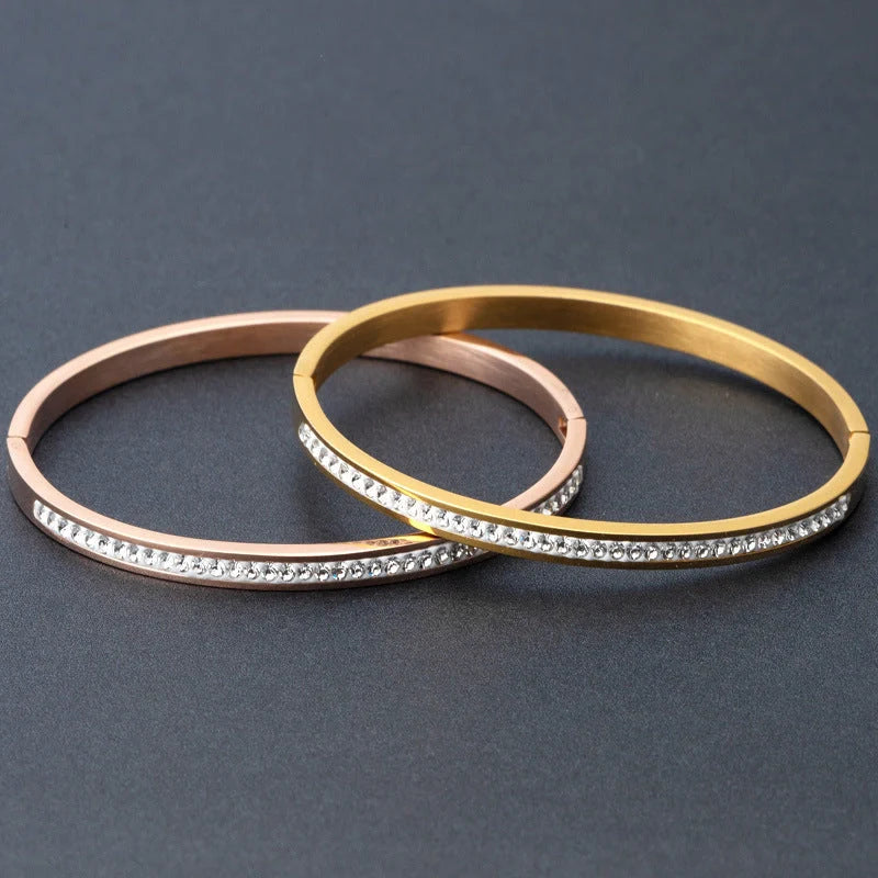 Elegant stainless steel bracelet with diamond accent, available in gold, rose gold, and steel finishes.