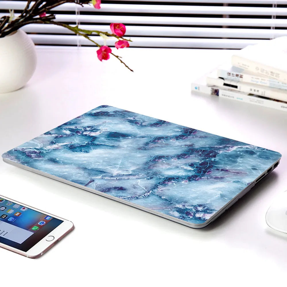 Plastic MacBook protective case in a marble pattern colour, shown next to a compatible Apple laptop.